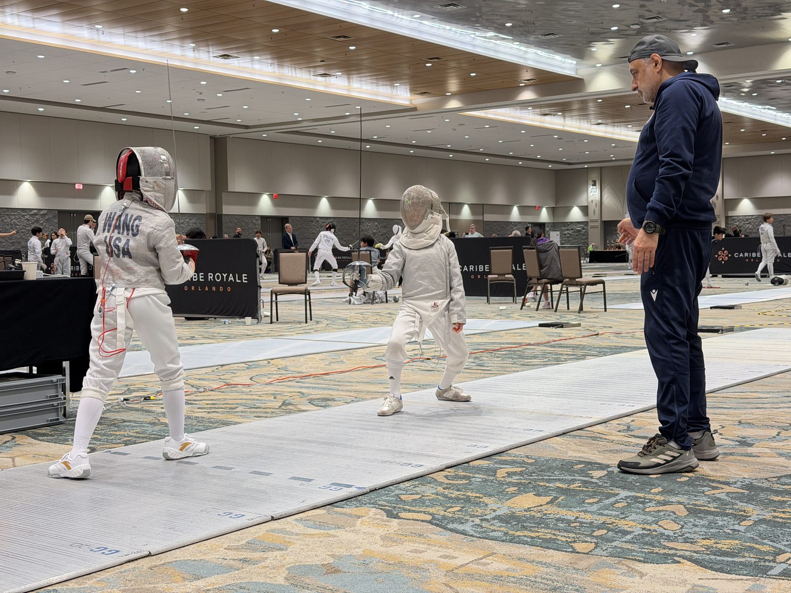 Coach Boris watching young CSFA fencer compete at national tournament